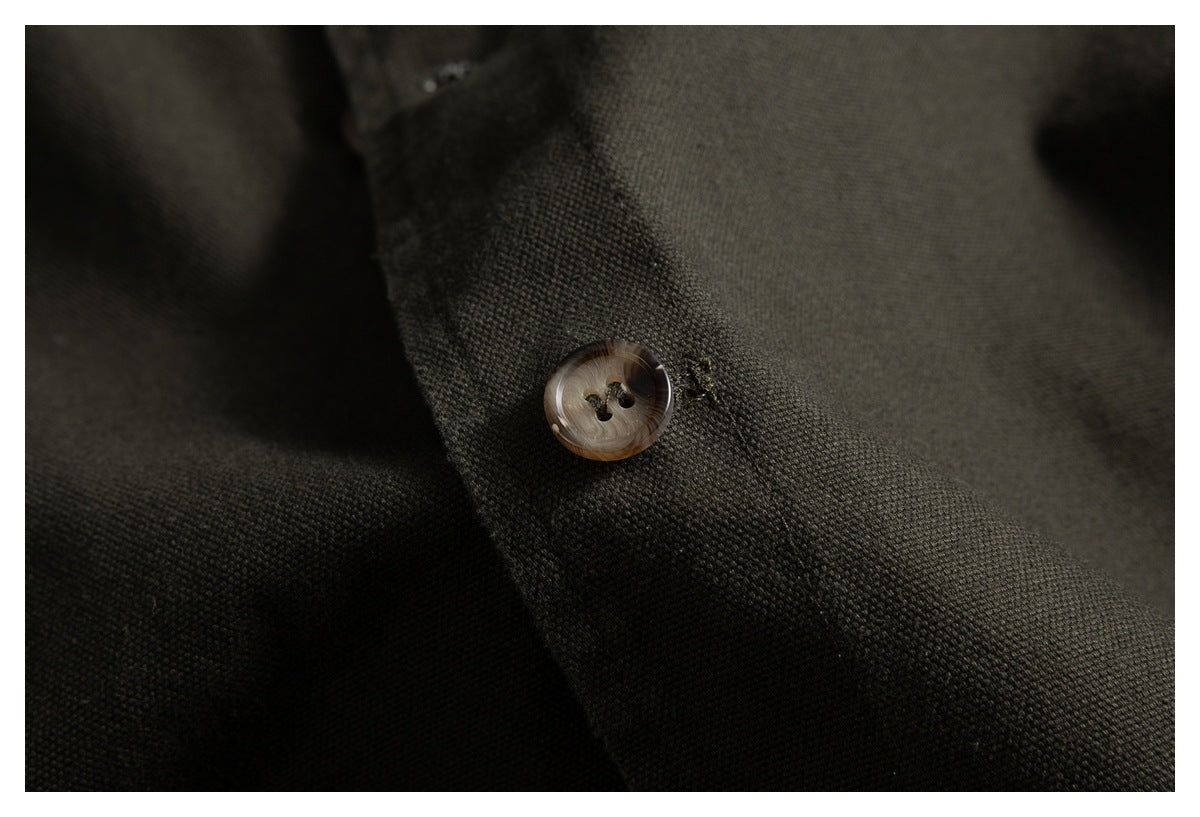 Close-up of a brown four-hole button on dark olive jacket fabric.