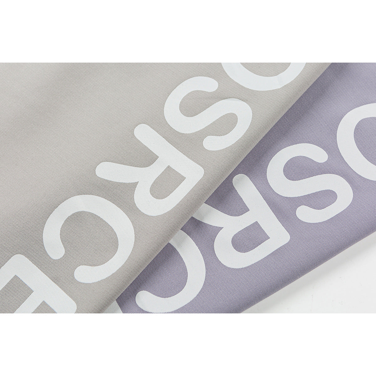 Close-up of large white lettering printed on light gray and lavender T-shirt fabric.
