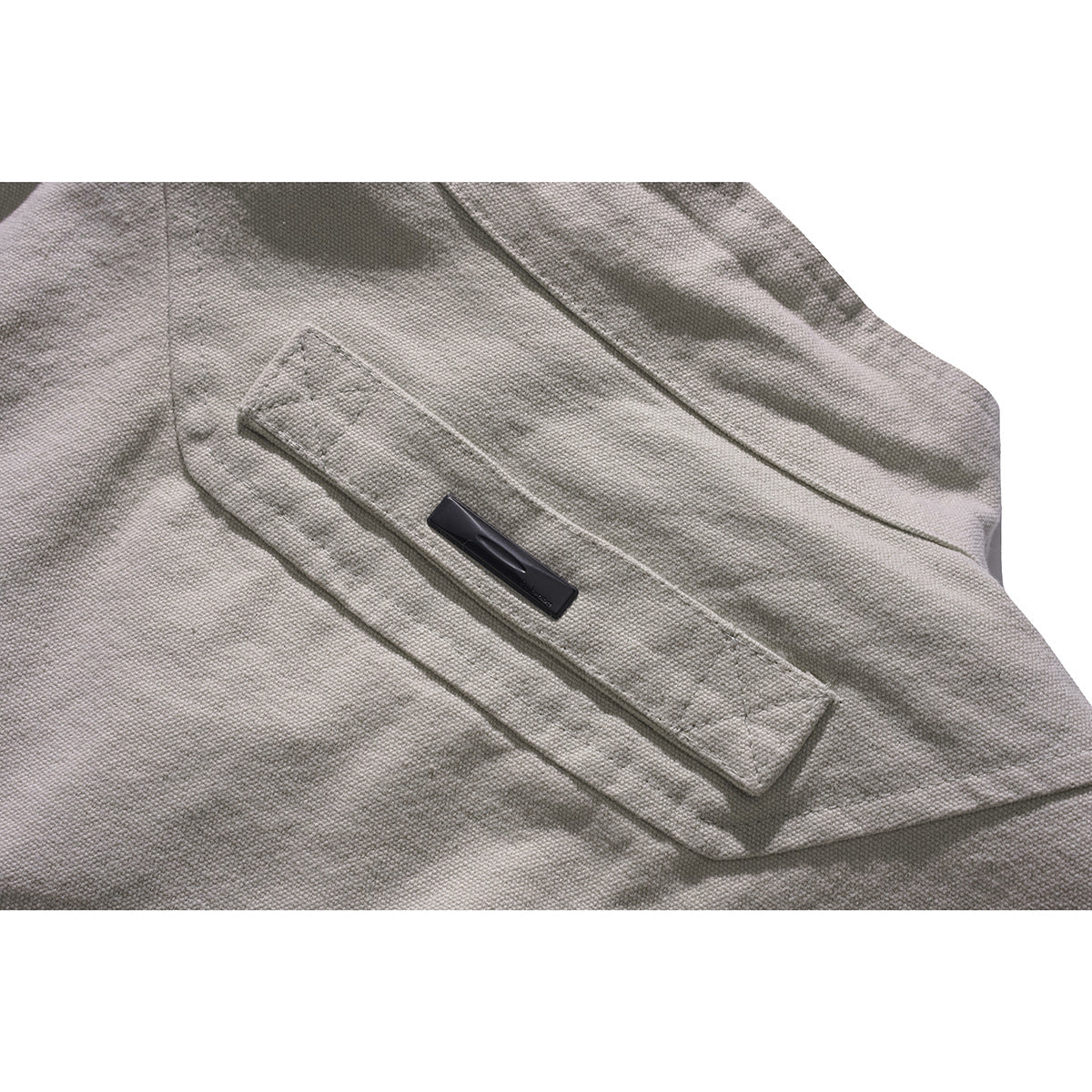 Close-up of a light gray jacket's flap pocket with a small dark tag.