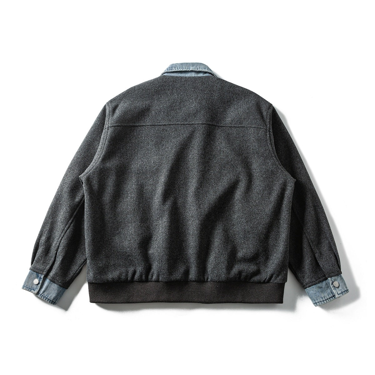 Back view of a charcoal gray jacket with a blue denim collar and cuffs and a ribbed hem.