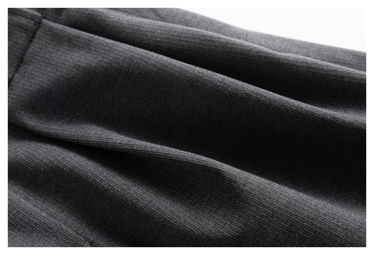 Close-up of the fine texture and folds in charcoal gray trouser fabric.