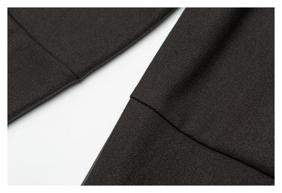 Close-up of a stitched seam on dark charcoal trouser fabric.