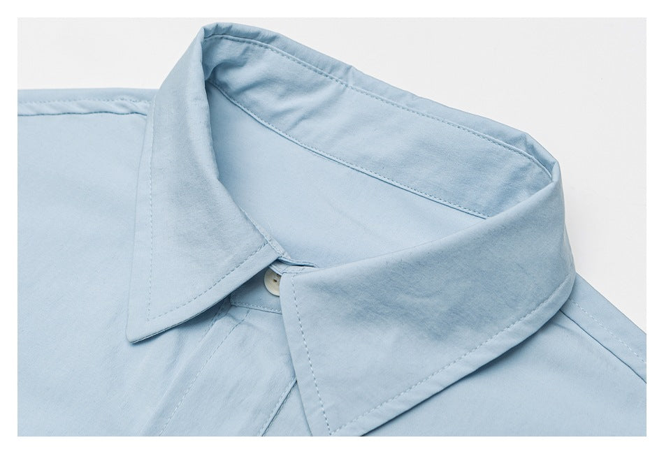 Close-up of the light blue shirt's pointed collar, stitching, and top button.