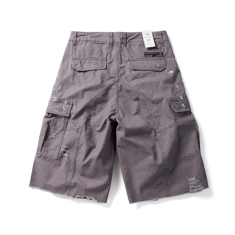 Back view of muted purple cargo shorts with flap pockets, distressed details, and raw hems.