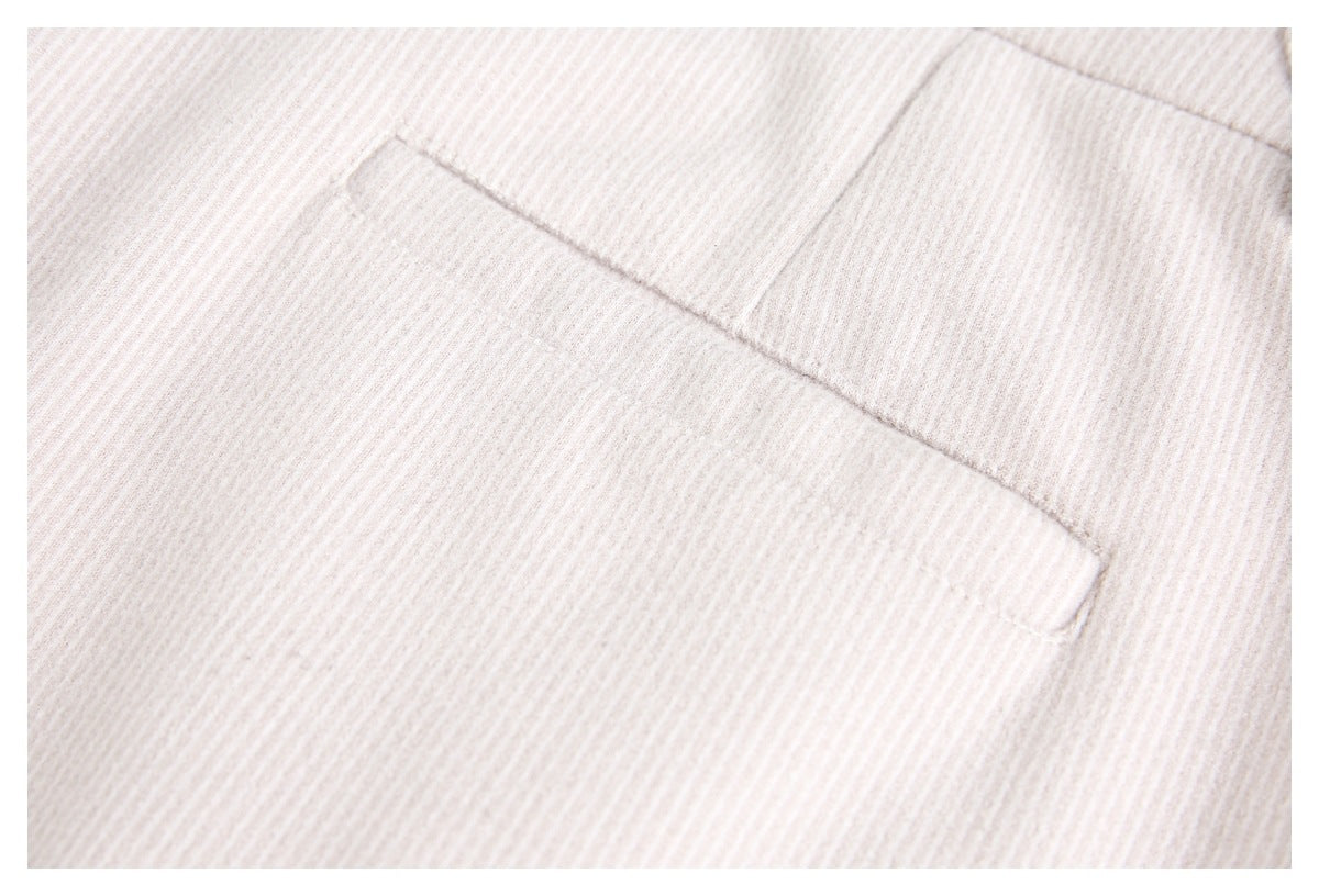 Close-up of pale ivory ribbed fabric with a stitched pocket edge.