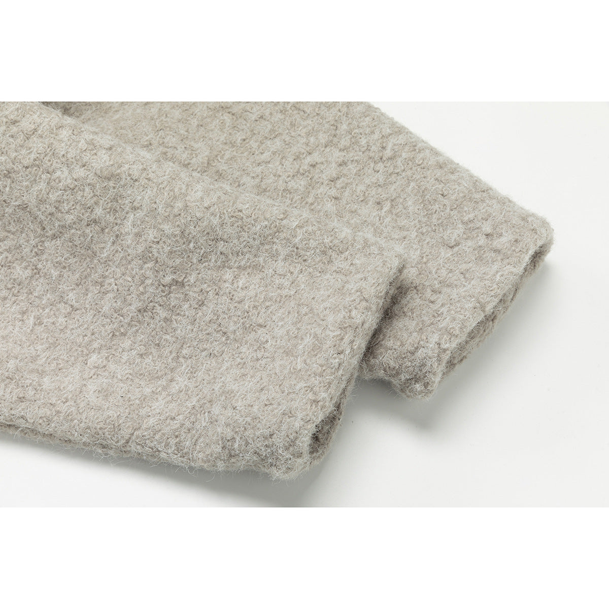 Close-up of the light beige jacket's sleeve and folded cuff, showing its fuzzy fabric texture.