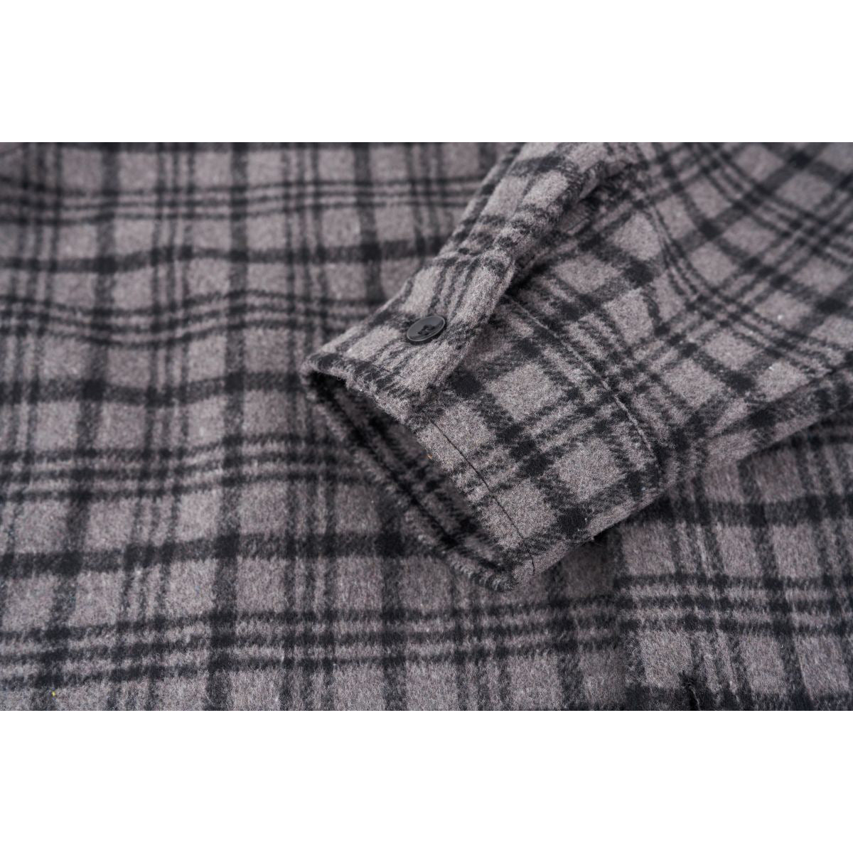 Close-up of a gray and black plaid shirt sleeve cuff with a black button.