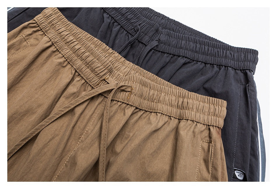 Close-up of tan and charcoal pants showing elastic waistbands, drawstrings, and pockets.