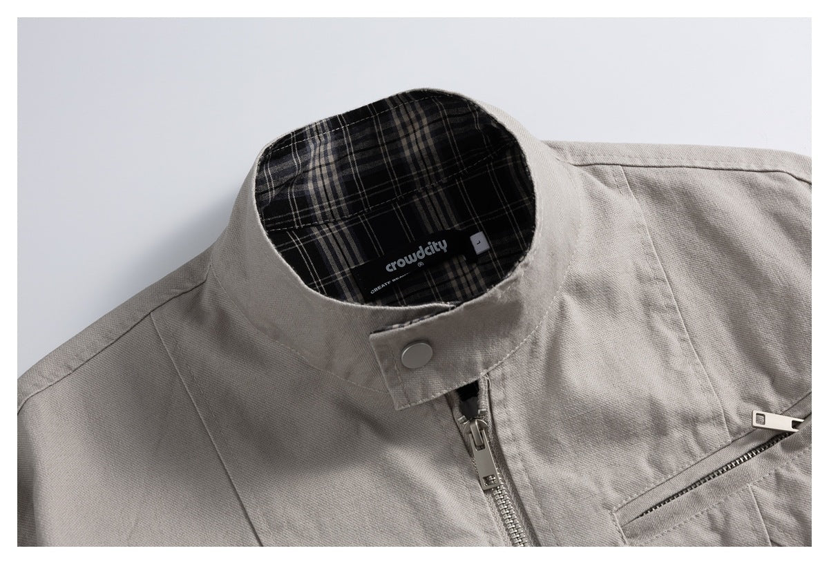Close-up of a light gray jacket collar, front zipper, and black plaid lining with a sewn neck label.