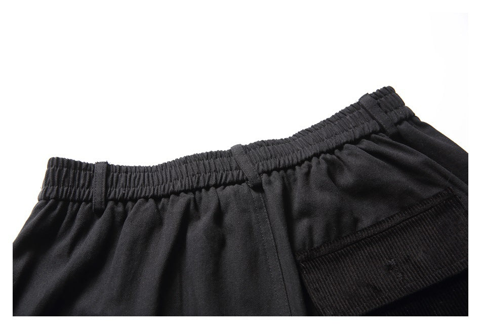 Close-up of the gathered elastic waistband and ribbed pocket detail on black shorts.
