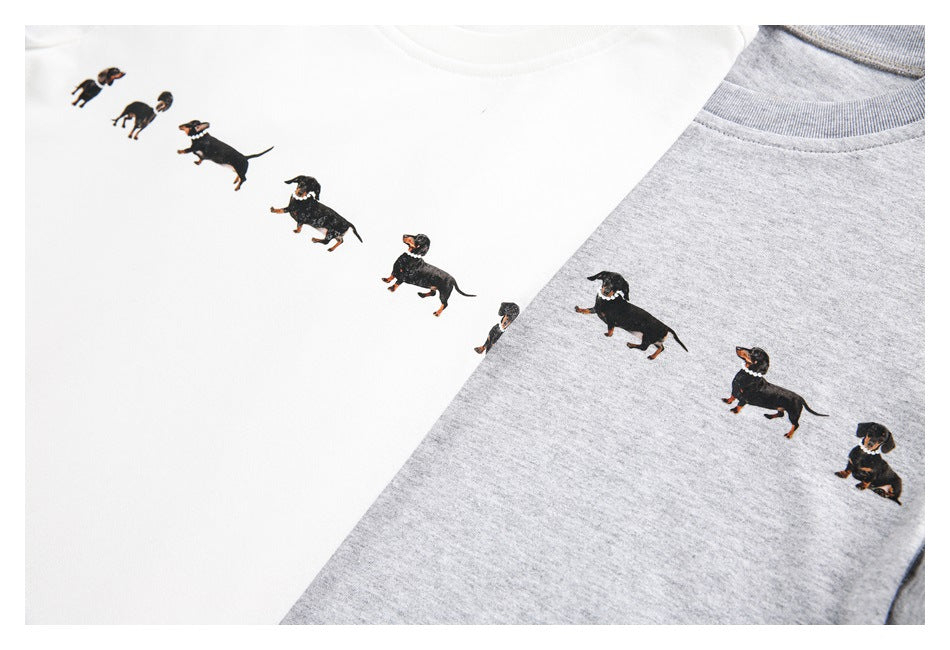 Close-up of white and light gray T-shirts printed with small dachshund illustrations.