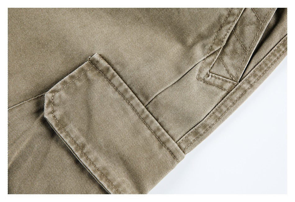 Close-up of khaki trousers with a rectangular flap pocket, belt loop and stitched seams.