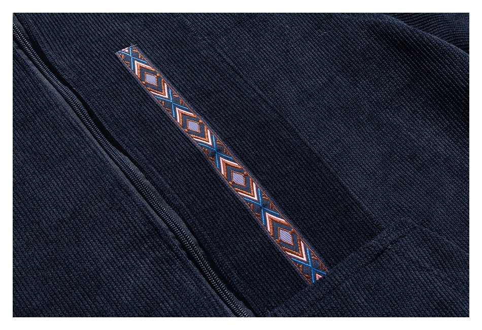 Close-up of a dark navy ribbed garment with a zipper and a narrow geometric-patterned trim.
