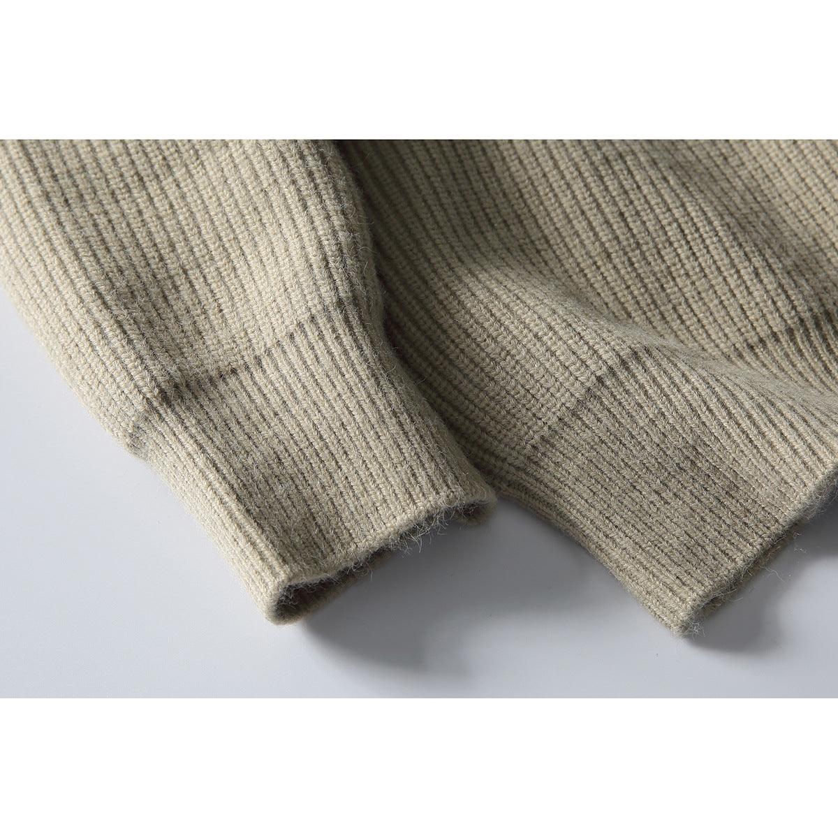 Close-up of the beige rib-knit sweater's sleeve cuff and bottom hem.