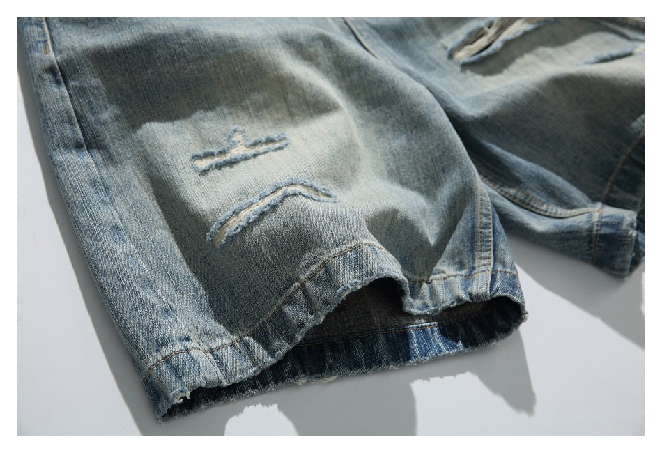 Close-up of faded blue jeans with small distressed slits and a raw, frayed leg hem.
