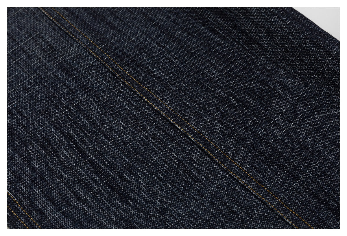Extreme close-up of the dark indigo fabric and a diagonal line of contrast stitching.