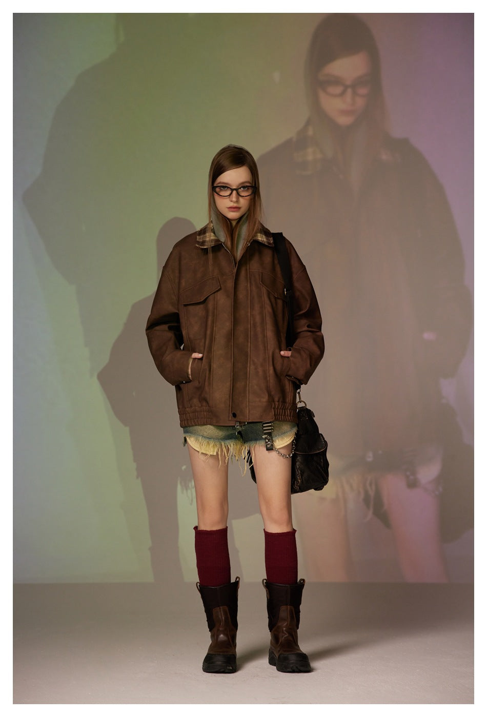 Front view of a model wearing an oversized brown jacket with a plaid collar and denim shorts.