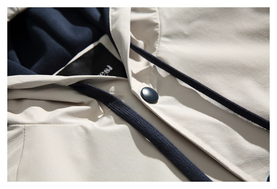 Close-up of an ivory jacket front with dark piping, a black snap button, and dark fabric visible inside.