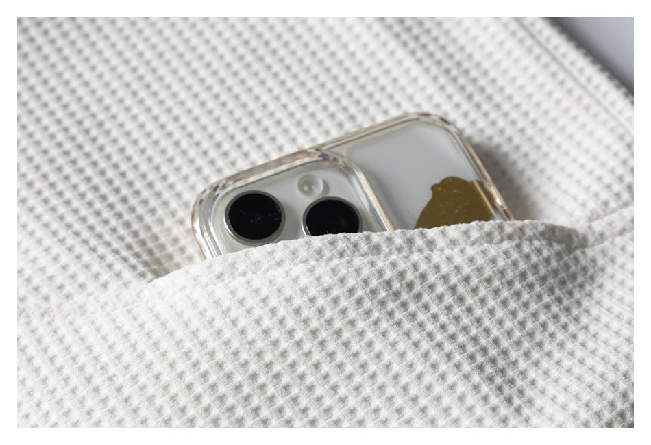 A smartphone tucked into a pocket on ivory waffle-knit fabric.