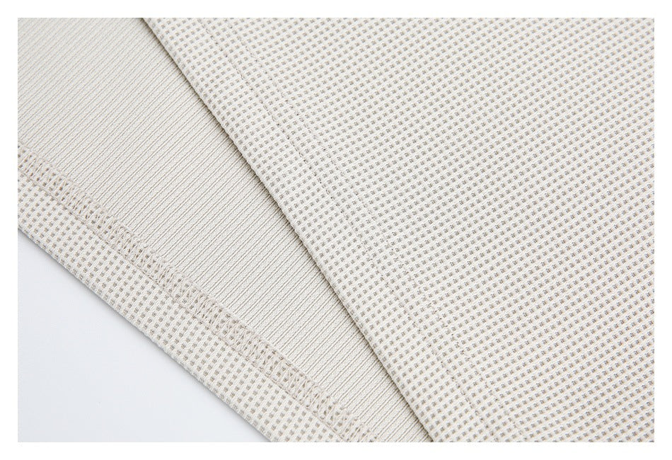 Close-up of cream patterned fabric beside a ribbed band and stitched seam.