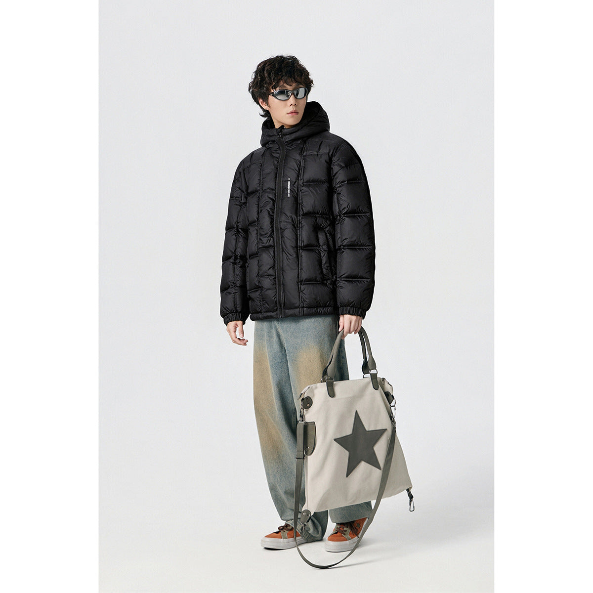 Model wearing a black hooded puffer jacket with a front zipper and horizontal quilting.