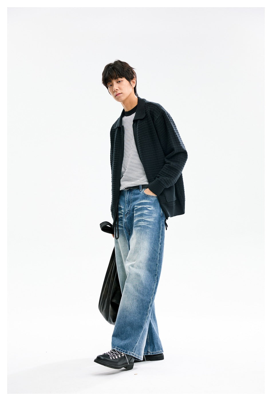 Three-quarter view of a model wearing a black textured knit jacket with a wide collar and patch pockets.