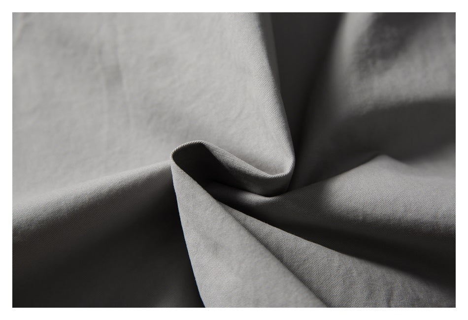 Close-up of light gray fabric draped into folds, showing its surface texture.
