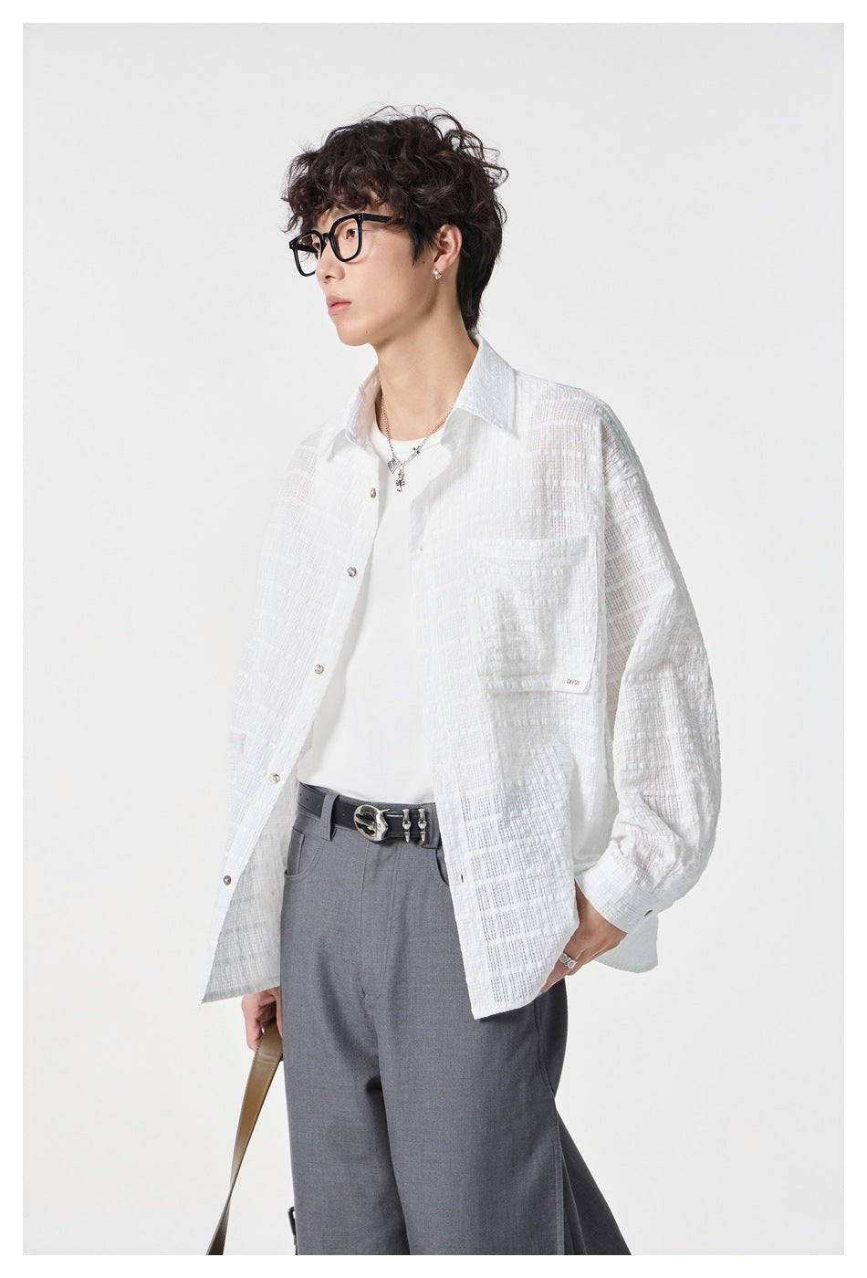 Close view of a model wearing an open white textured button-up shirt over a white tee.