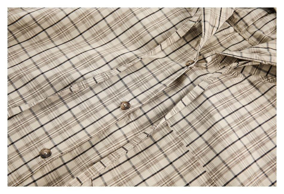Close-up of a cream plaid shirt's button front and chest pocket.