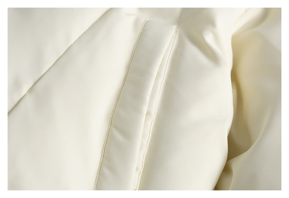 Close-up of a stitched panel seam on pale cream garment fabric.