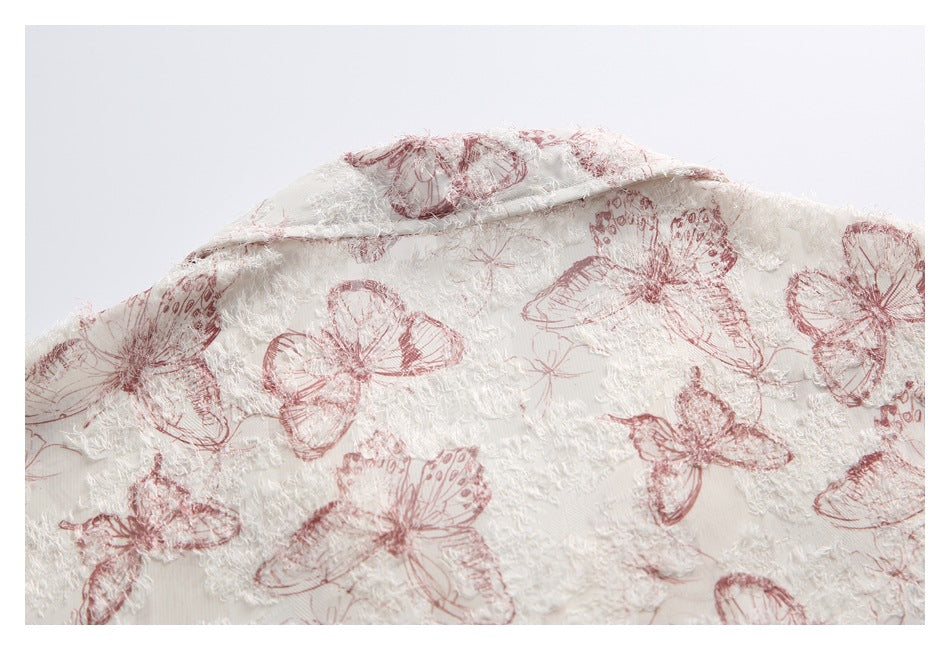 Close-up of a folded section of ivory textured fabric with a dusty rose butterfly print.