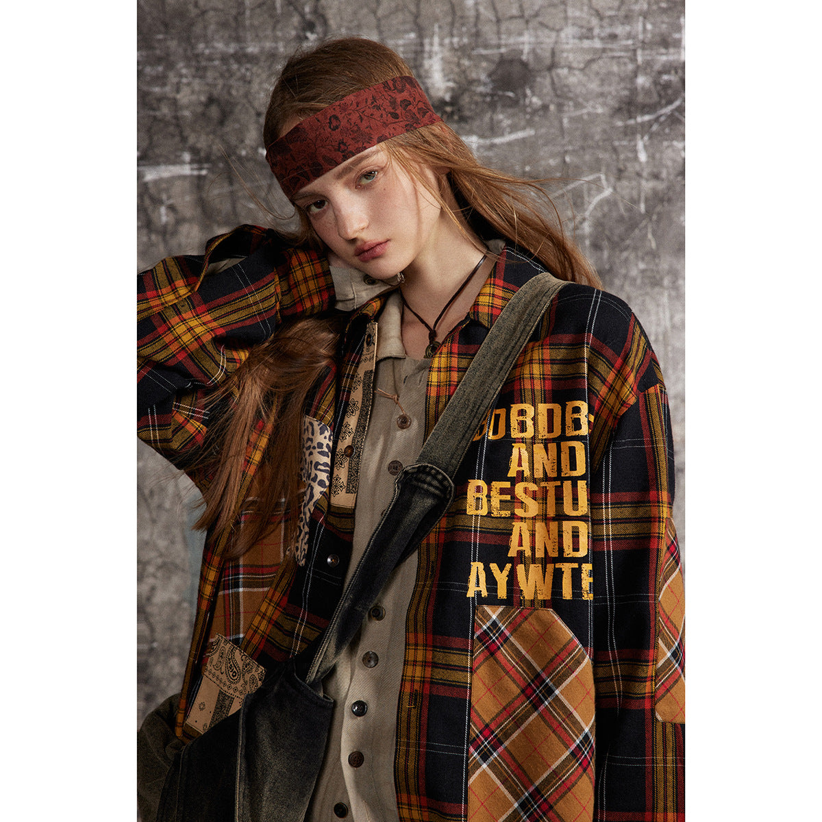 Close view of a model wearing a black and red plaid shirt-jacket with patchwork pockets and yellow lettering.