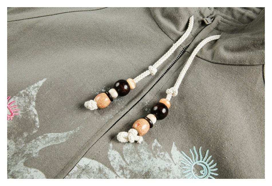 Close-up of beaded cream zipper pulls and colorful stitched motifs on the jacket front.