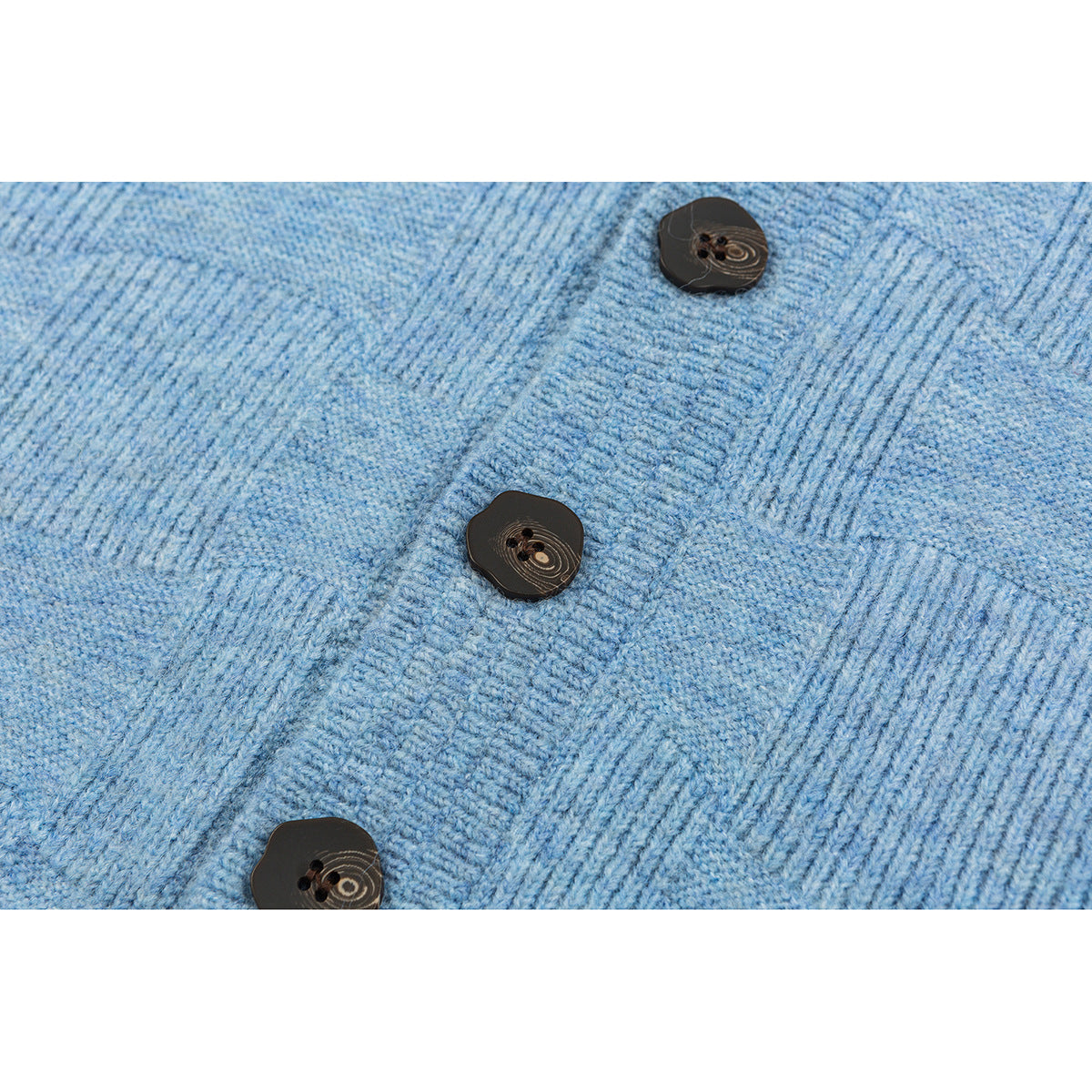 Close-up of a blue textured knit cardigan with three dark buttons along the front placket.