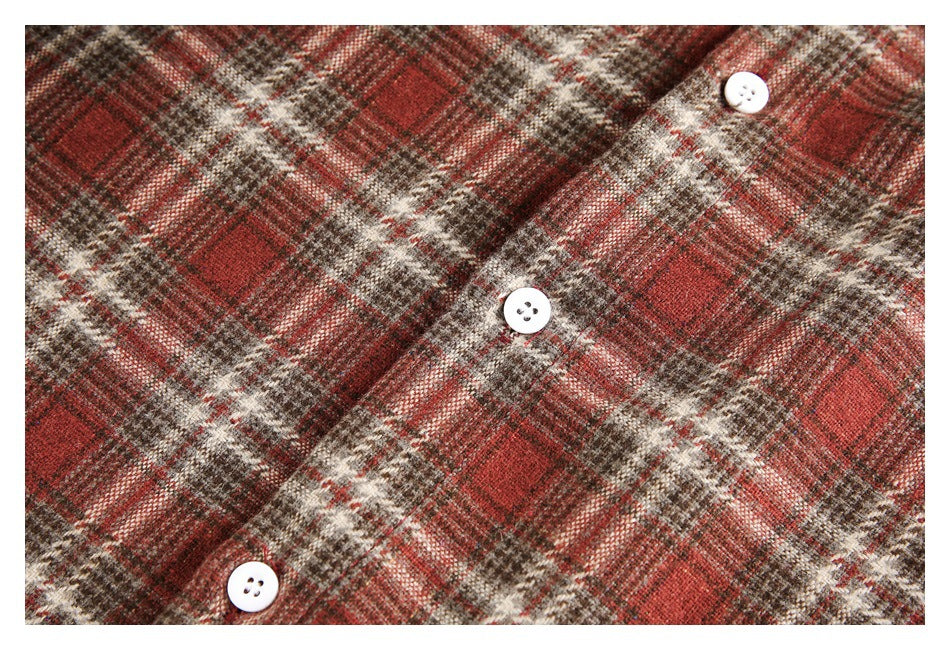 Close-up of red, brown, and cream plaid fabric with three white buttons.