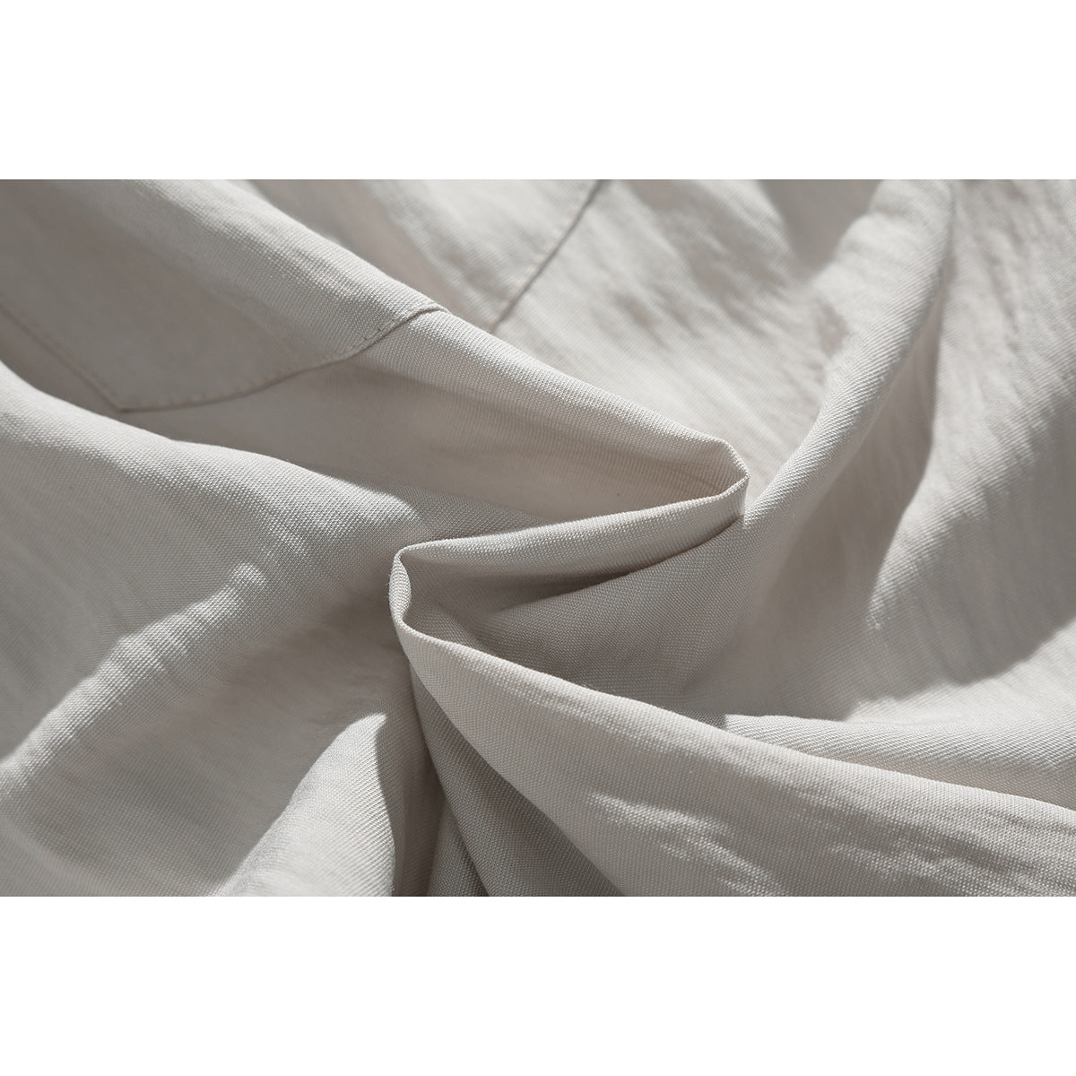 Close-up of softly folded off-white shorts fabric and its fine surface texture.