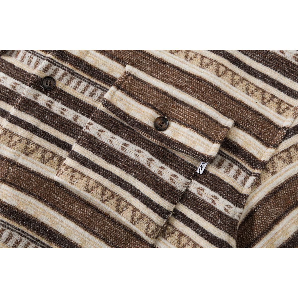 Close-up of a chest pocket and dark buttons on a brown and cream geometric-striped shirt.