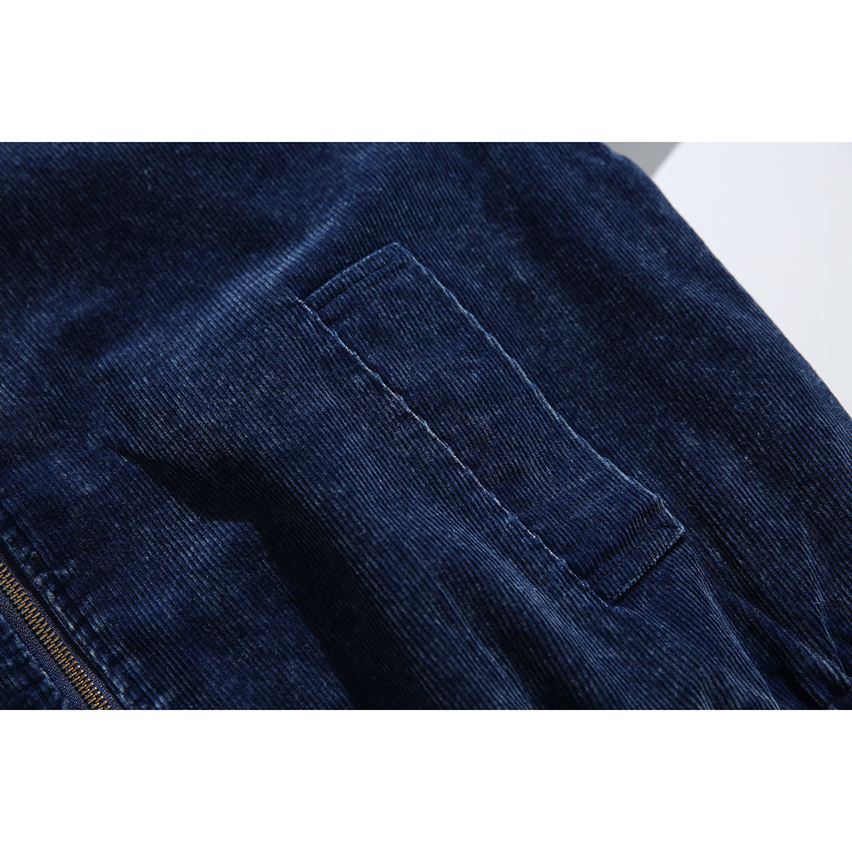 Close-up of a rectangular welt pocket on the dark navy ribbed jacket.