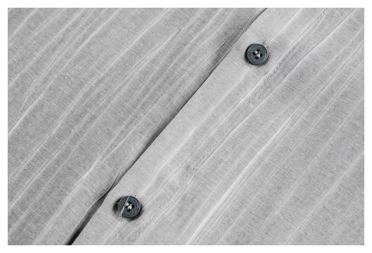 Close-up of dark buttons and stitched placket on gray textured fabric.