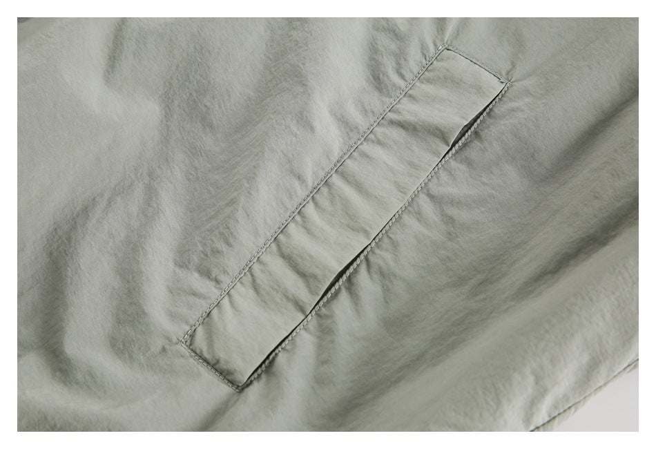 Close-up of a long slanted welt pocket on a pale sage jacket panel.
