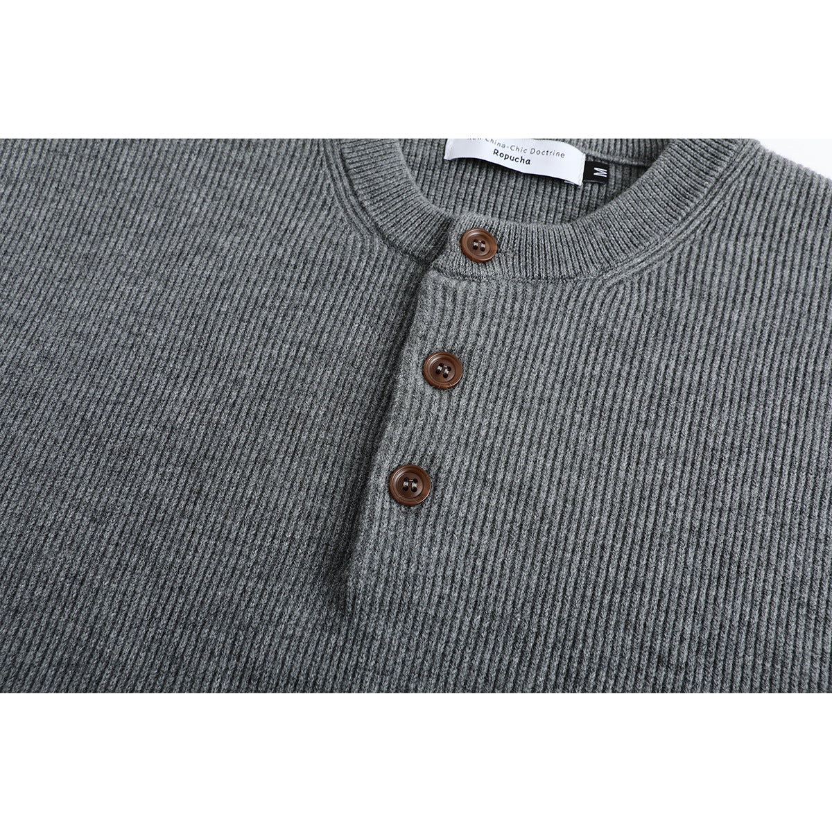Close-up of a gray ribbed sweater's round neckline and three brown buttons.