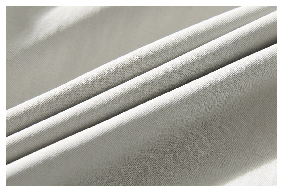 Close-up of light gray fabric folded to show its fine diagonal texture.