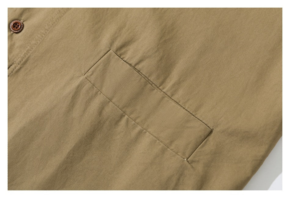 Close-up of a tan garment's rectangular pocket and brown button.
