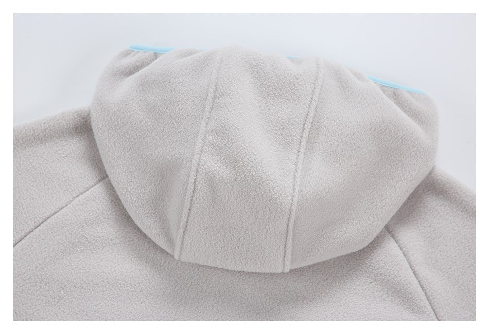 Close-up of the hood and stitched panels on a pale gray fuzzy garment, with light blue trim visible behind.
