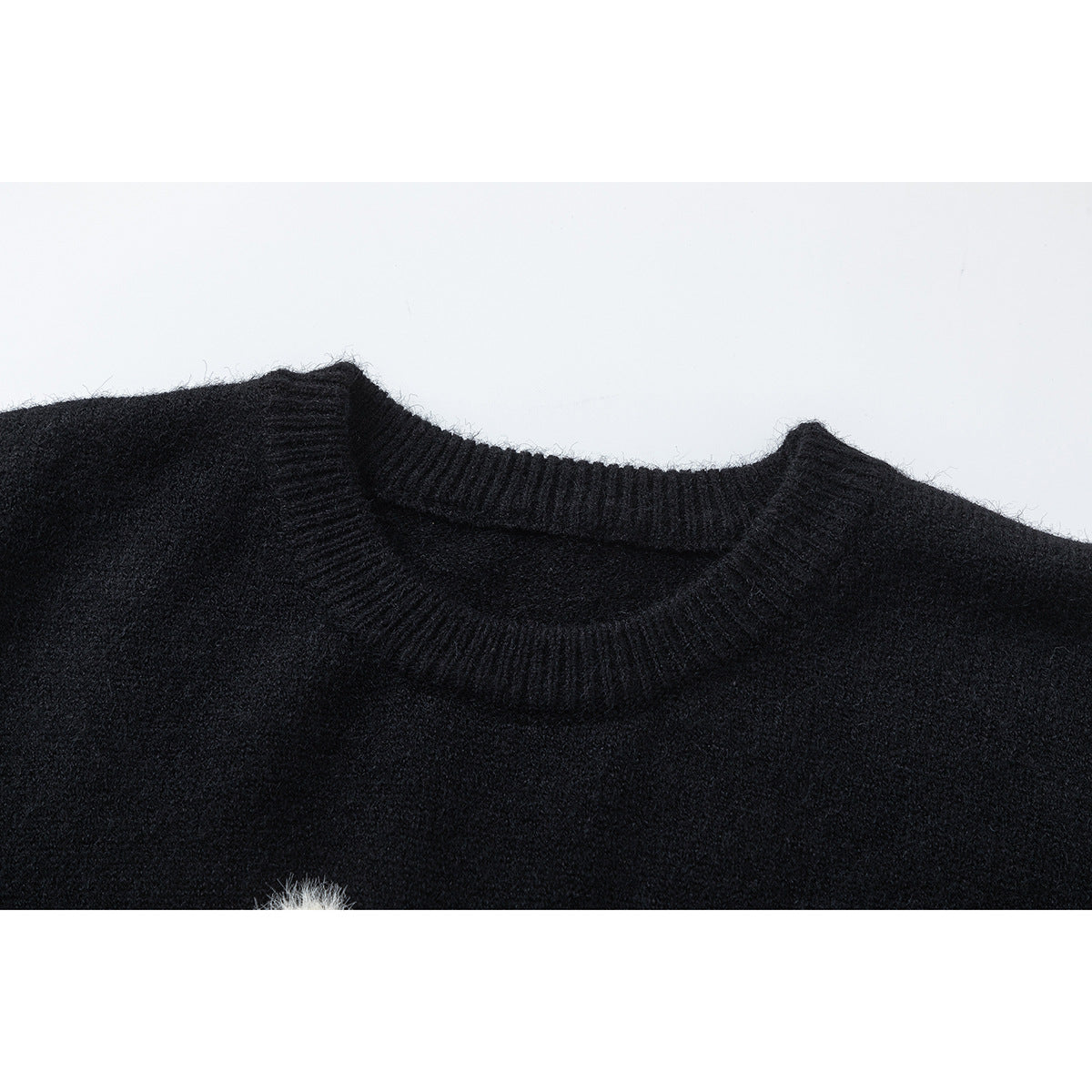 Close-up of a black sweater's ribbed crew neckline and upper chest.