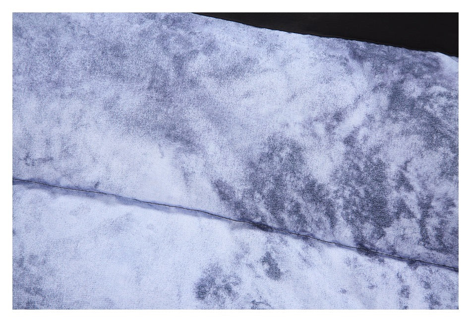 Close-up of blue-gray mottled fabric with a curved seam and a black fabric edge.