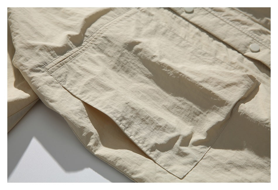 Close-up of a large stitched patch pocket on the light beige jacket.