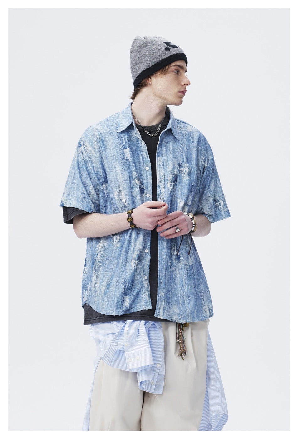 Closer view of a model wearing a blue distressed-pattern short-sleeve button-up over a black tee.