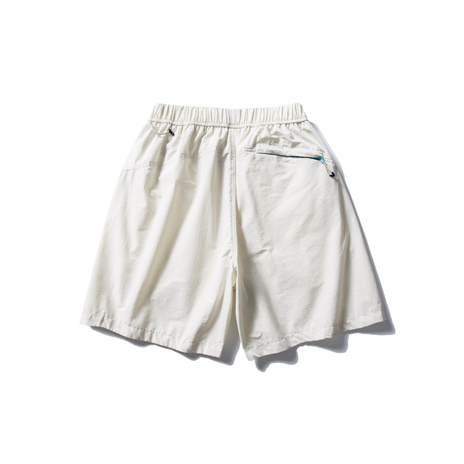 Back view of off-white shorts with an elastic waistband and a zip pocket.