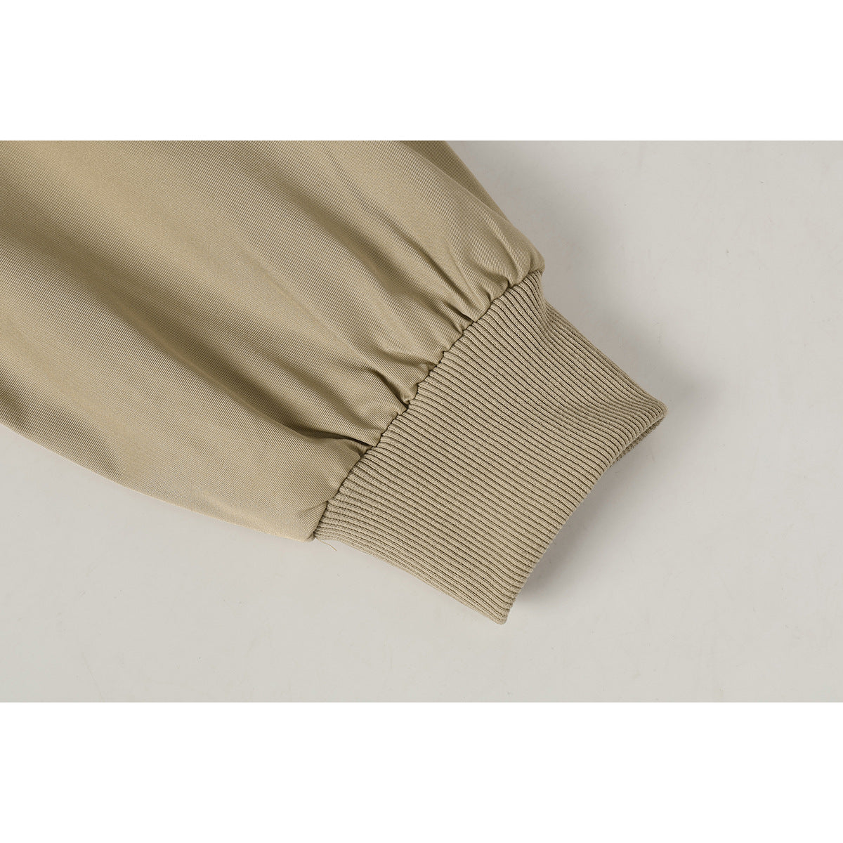 Close-up of a tan jacket sleeve gathered into a wide ribbed knit cuff.